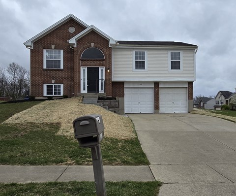 A brick house with a white garage door and a mailbox in front.